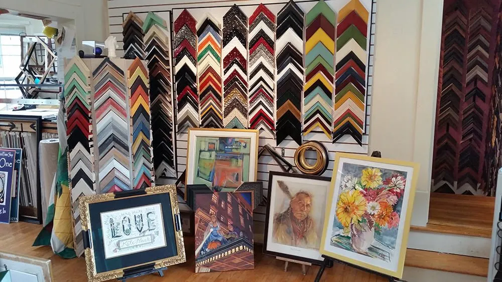 A wall of frame corner samples above framed art on display in the shop