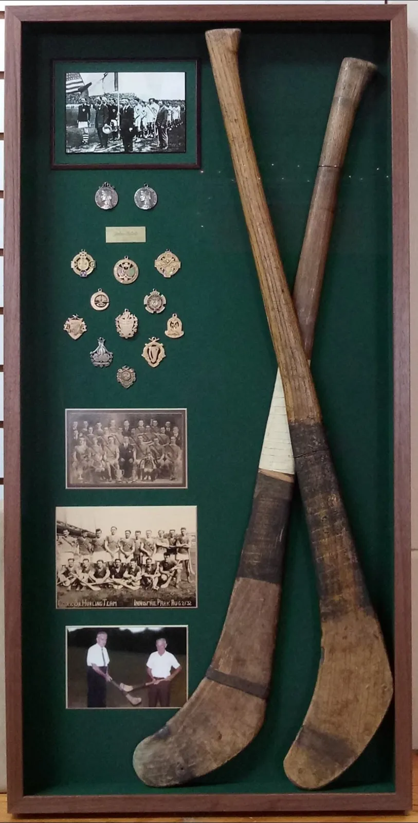 Tall shadow box with two wooden sticks, old team photographs and pins