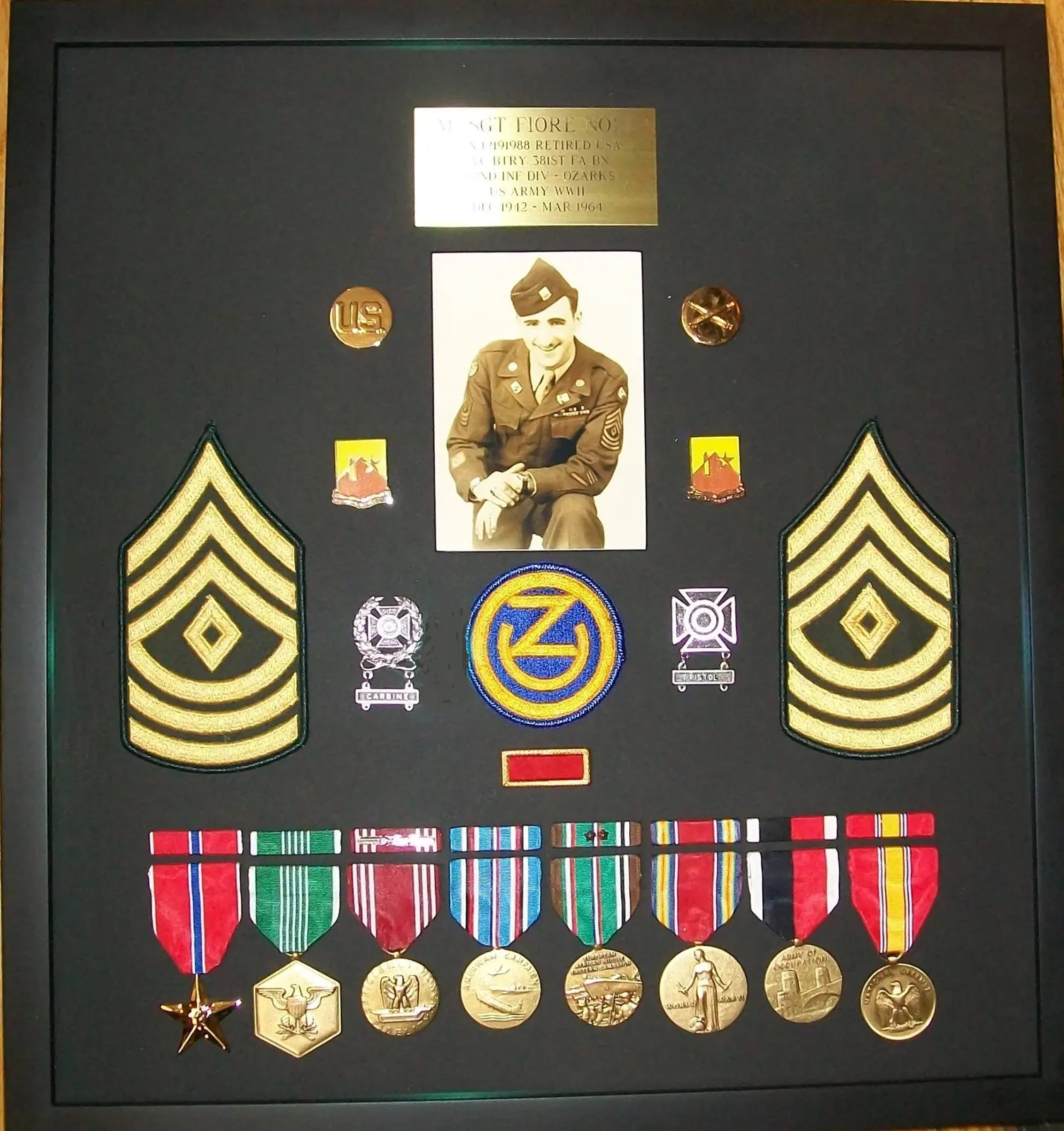 Military shadow box with a portrait, sergeant stripes, insignia and a row of medals